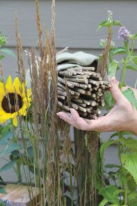 person placing bamboo stakes wrapped in purlap amongst various plants